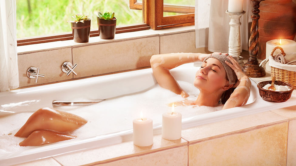 Woman relaxing in bathtub with open window