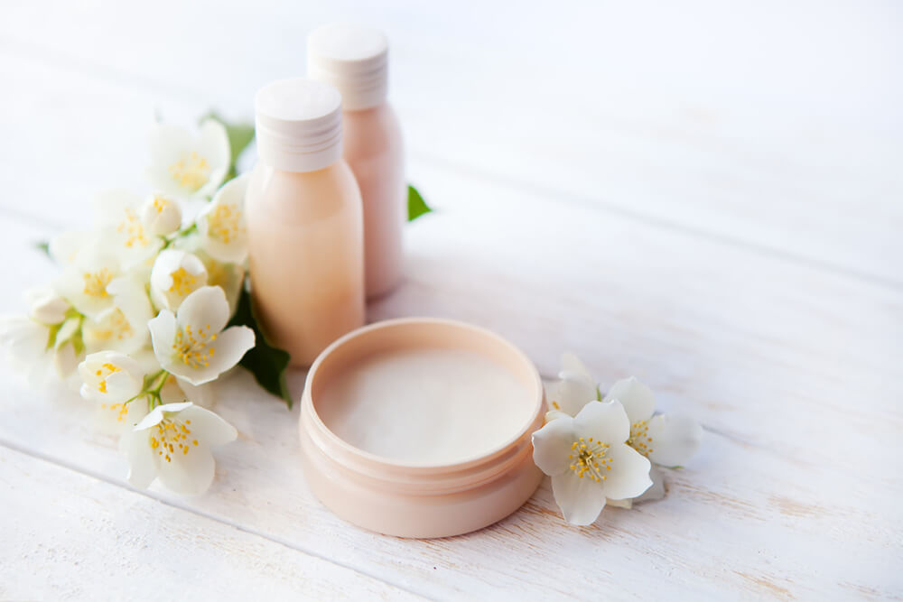 Open wellness cream product & scented jars decorated with flowers