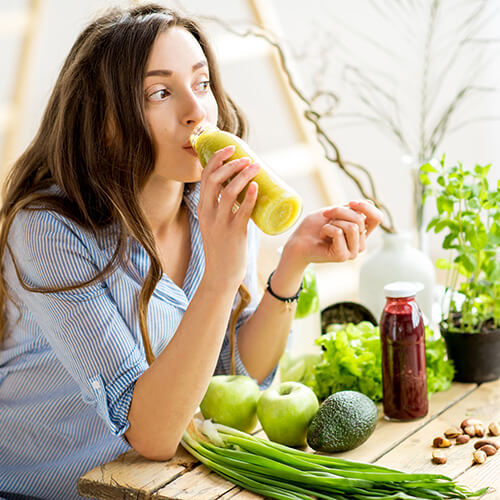 Young woman drinking healthy smoothie from fruits and vegetables