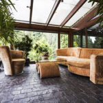 Noble cold winter garden with sofa, glass table and big plants