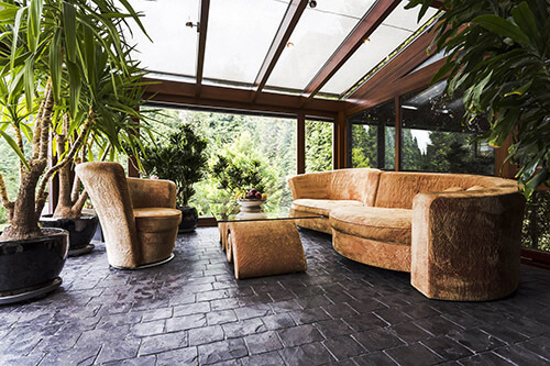 Noble cold winter garden with sofa, glass table and big plants