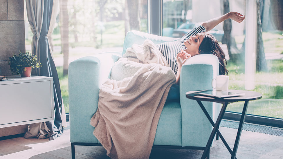 Woman stretches joyfully in armchair in light-flooded living room