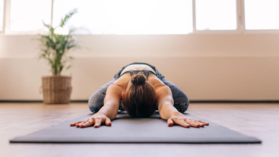 Woman stretches on mat in meditation room