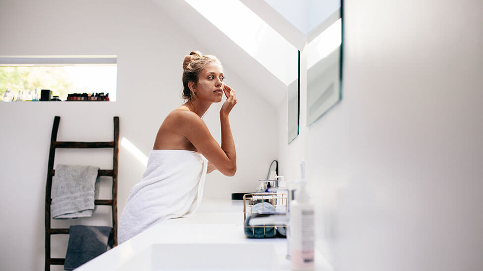 Woman puts cream on her body in bath to protect against pimples