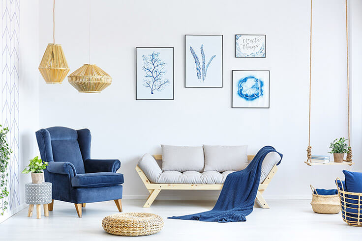 Bright, tidy living room in blue, with armchair, sofa, blanket, swing and pictures on the wall