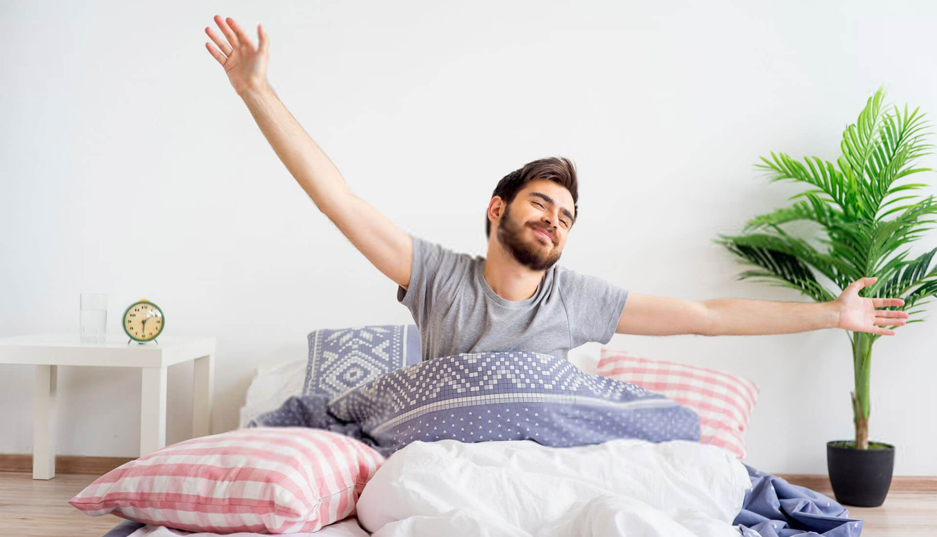 Young man happily stretching while getting up in the morning in bed