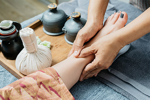 Foot reflexology massage, with the hands of the masseur and one leg of the person being massaged visible