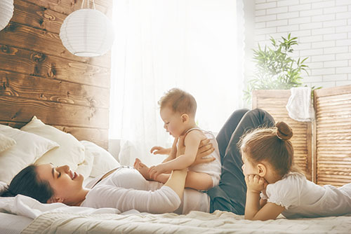 Mother lies together with 2 children in family bed