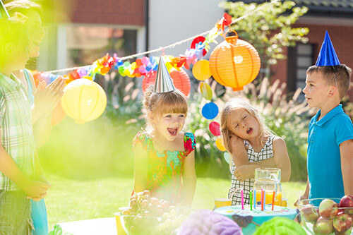 Children playing birthday games outside in garden