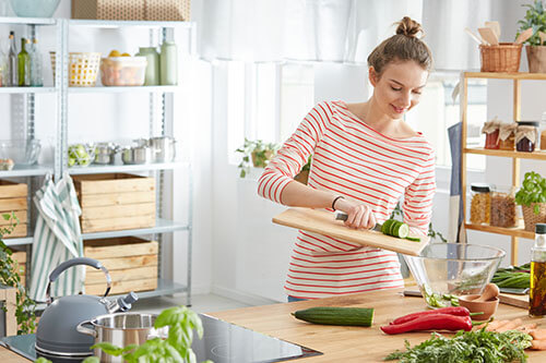 Young woman prepares healthy meal from fruits and vegetables in kitchen