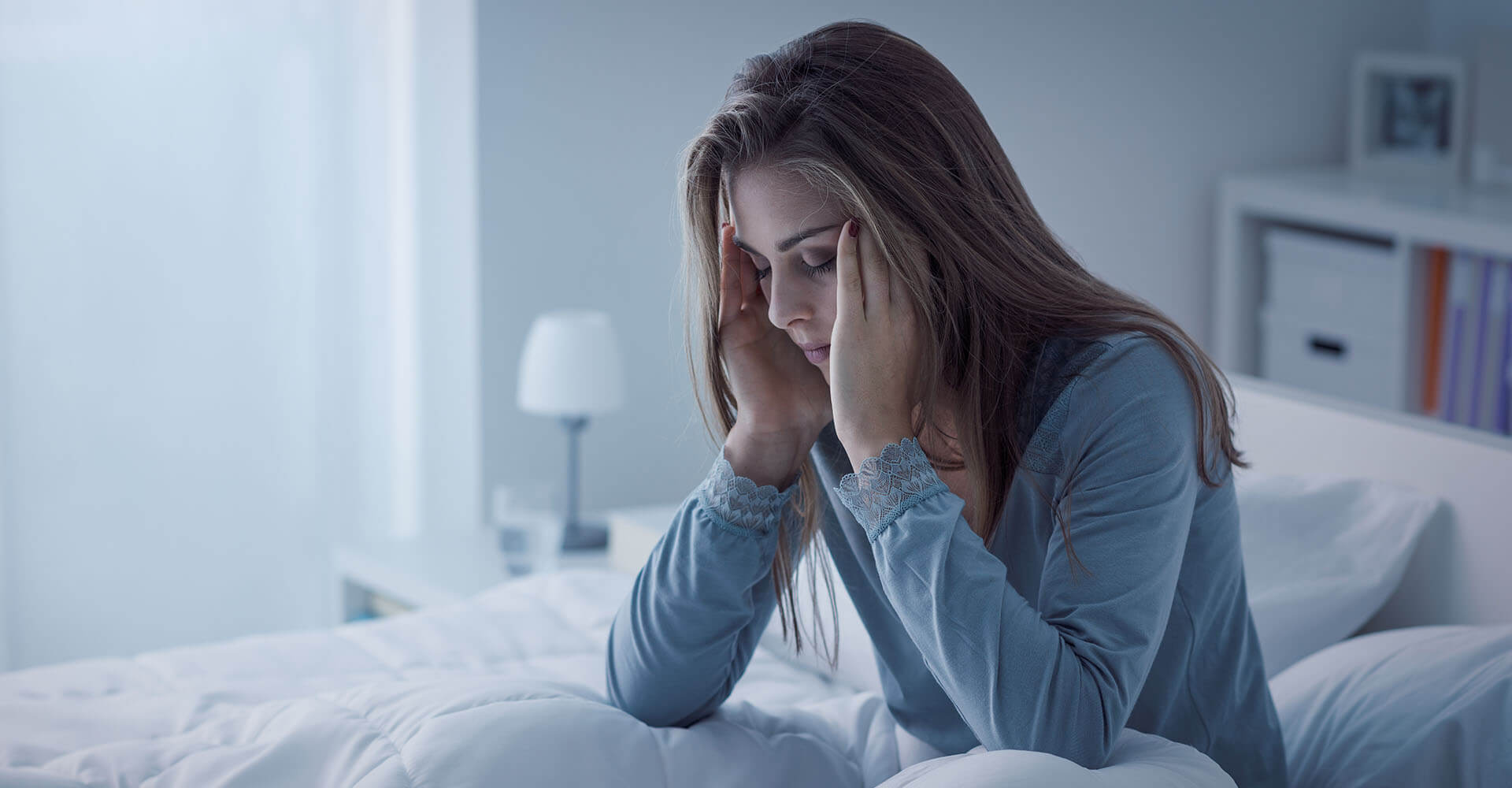 Woman wakes up unslept and unrelaxed in bed and apparently has a headache