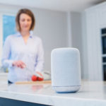 Woman in kitchen in background - smart speaker in foreground