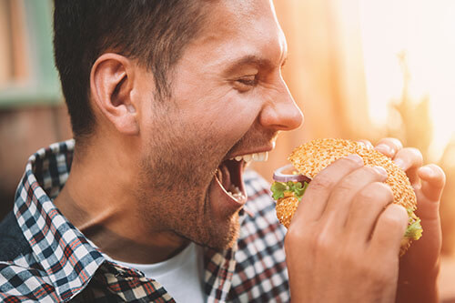 Man is about to bite into a large burger