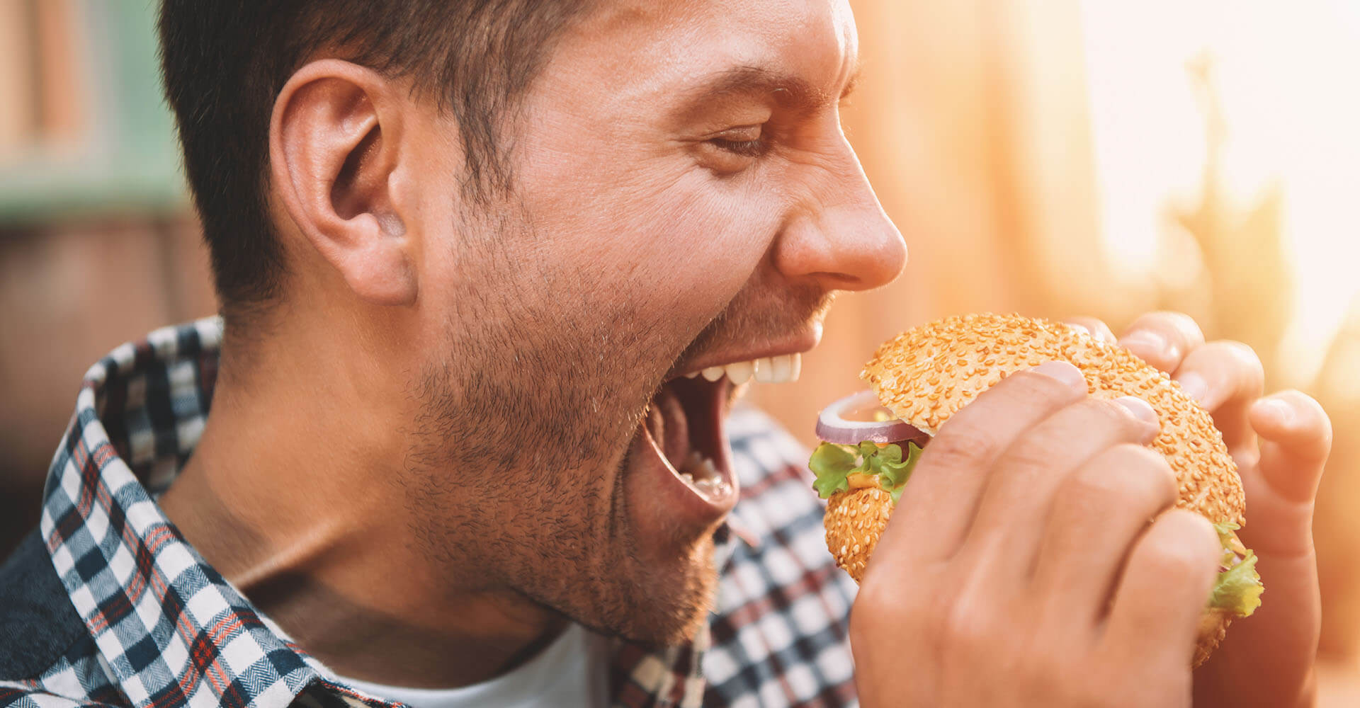 Man with obvious ravenous appetite is about to bite into a large burger