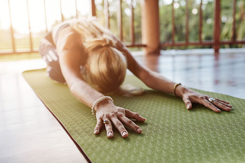 Woman doing yoga exercise on green mat at home