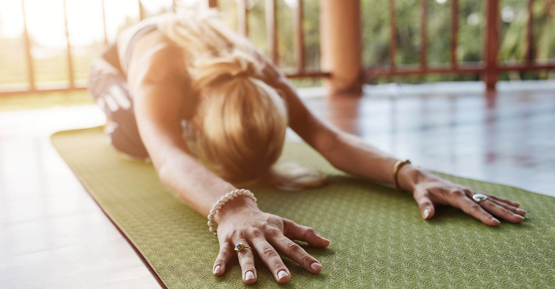 Woman doing yoga exercise on green mat at home