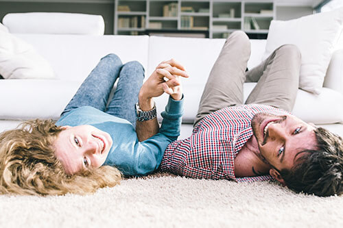 Couple warming up together in living room on the floor for yoga exercises