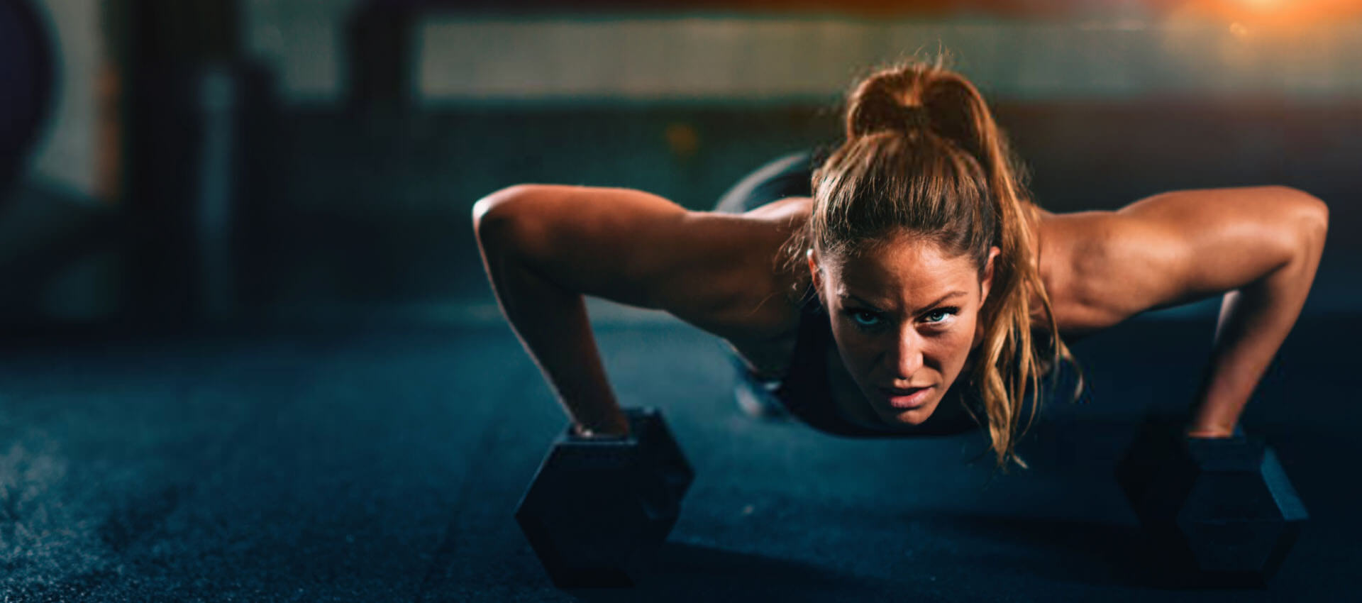 Woman doing pushups with dumbbells