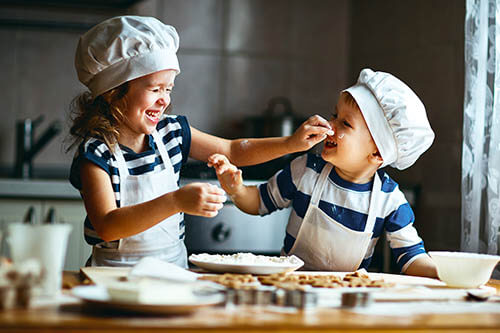 Small children bake together in kitchen