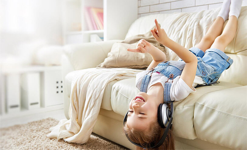A girl lying upside down on the bed listening to music through headphones