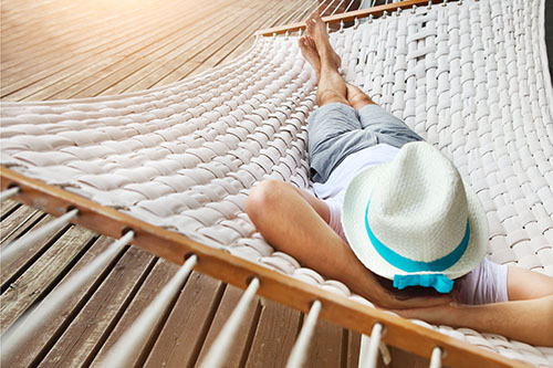 Man with hat relaxing or sleeping in hammock