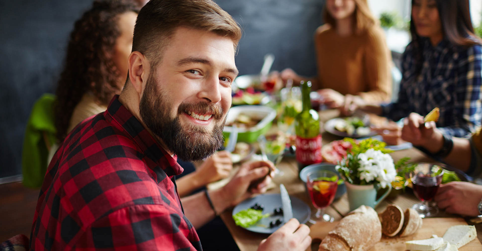 man sitting smiling at lunch table with friends and eating