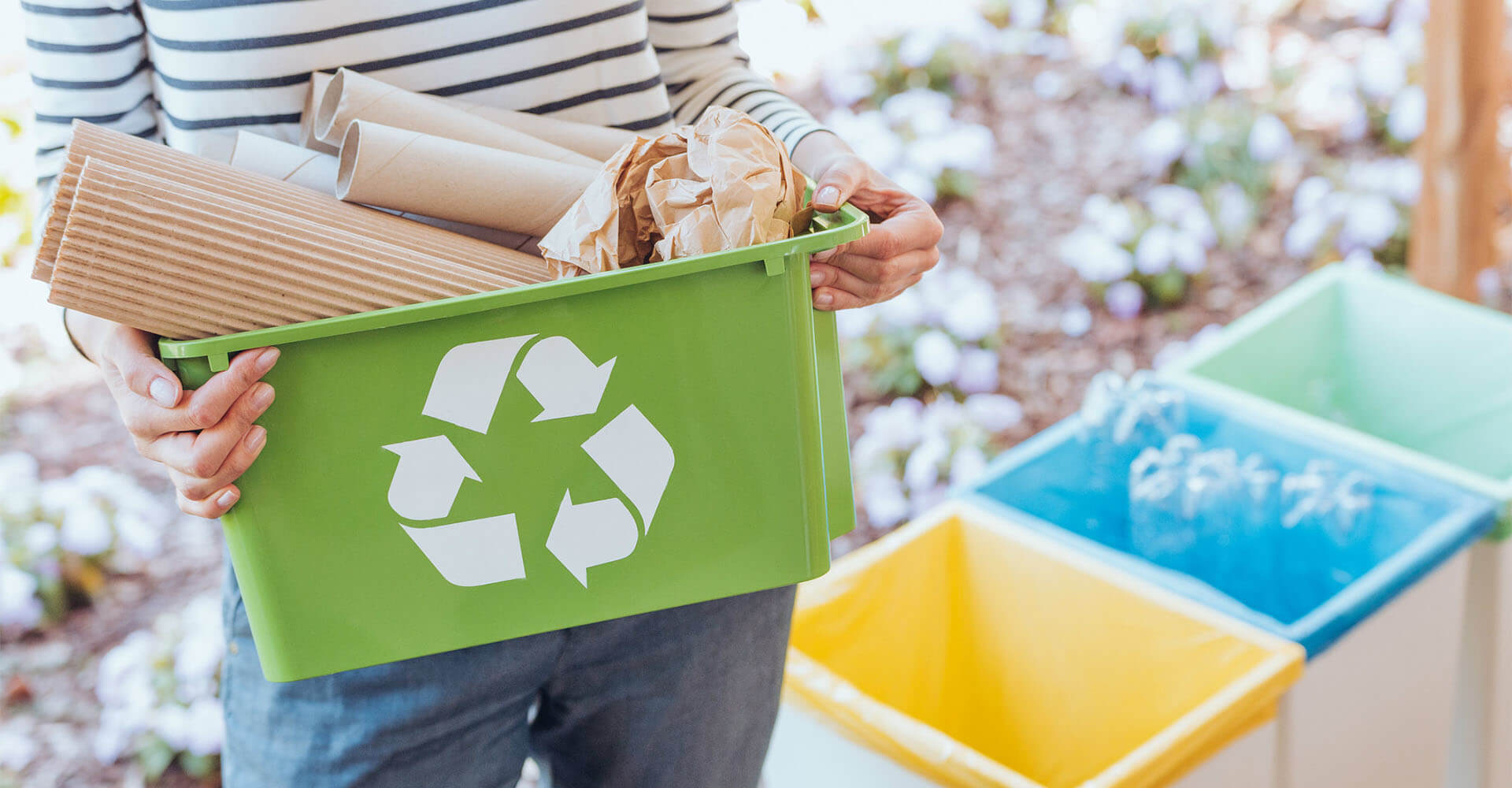 Woman taking garbage to garbage can in front of house