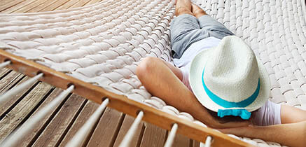 Man with hat relaxes or sleeps in hammock