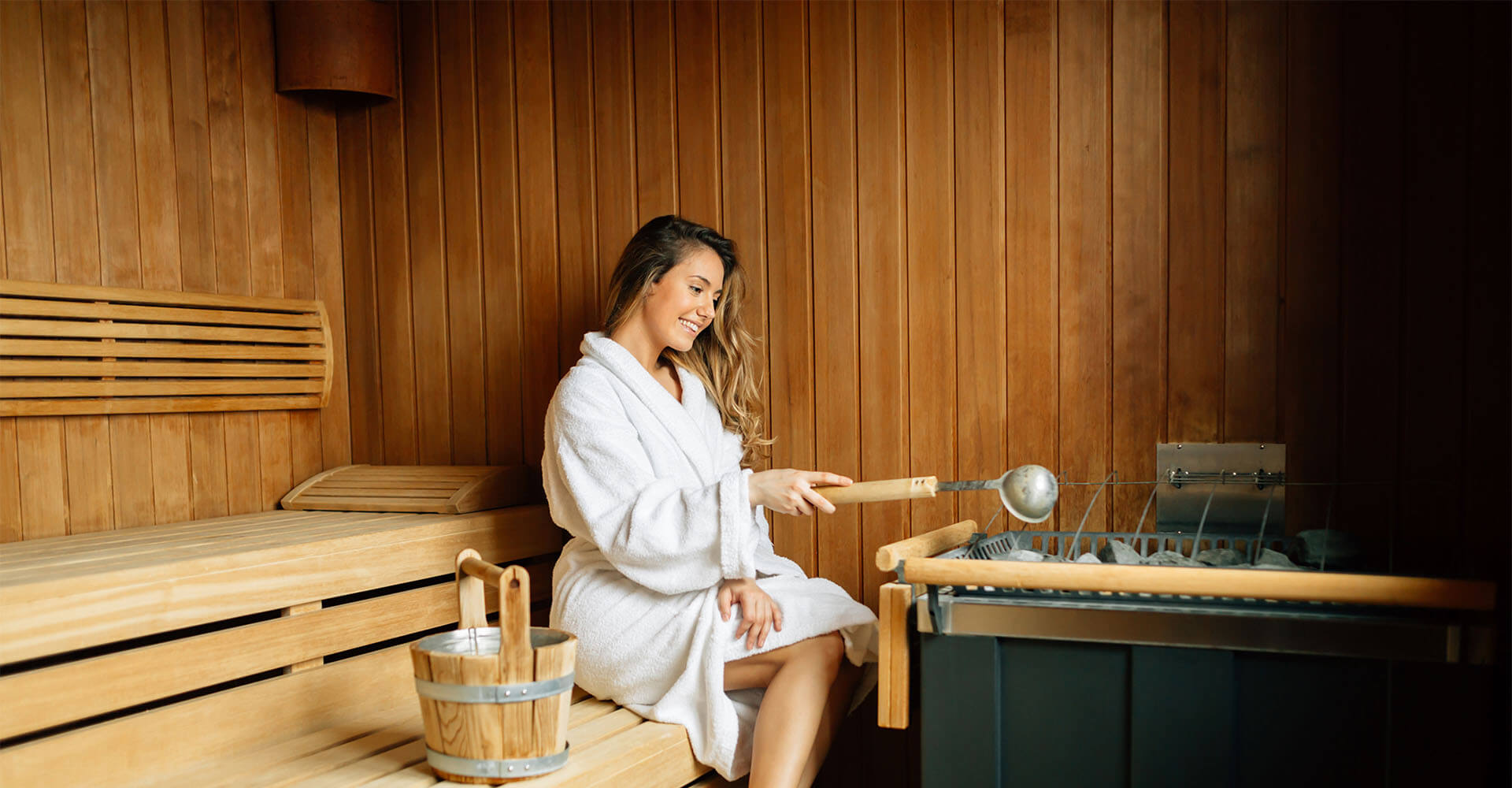 Woman sitting in sauna with bathrobe making infusion to lose weight in sauna