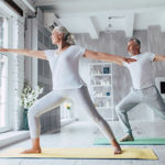 Elderly senior couple does yoga exercises at home