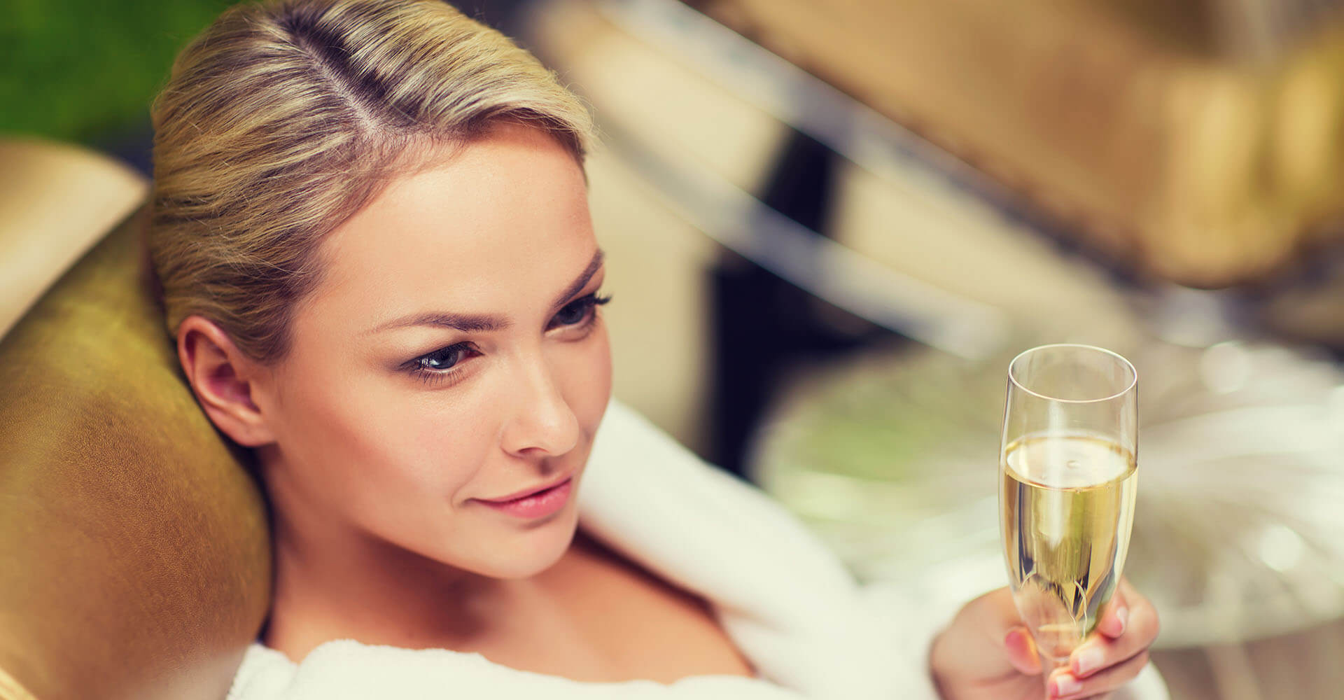 Beautiful woman relaxing after sauna with champagne in hand