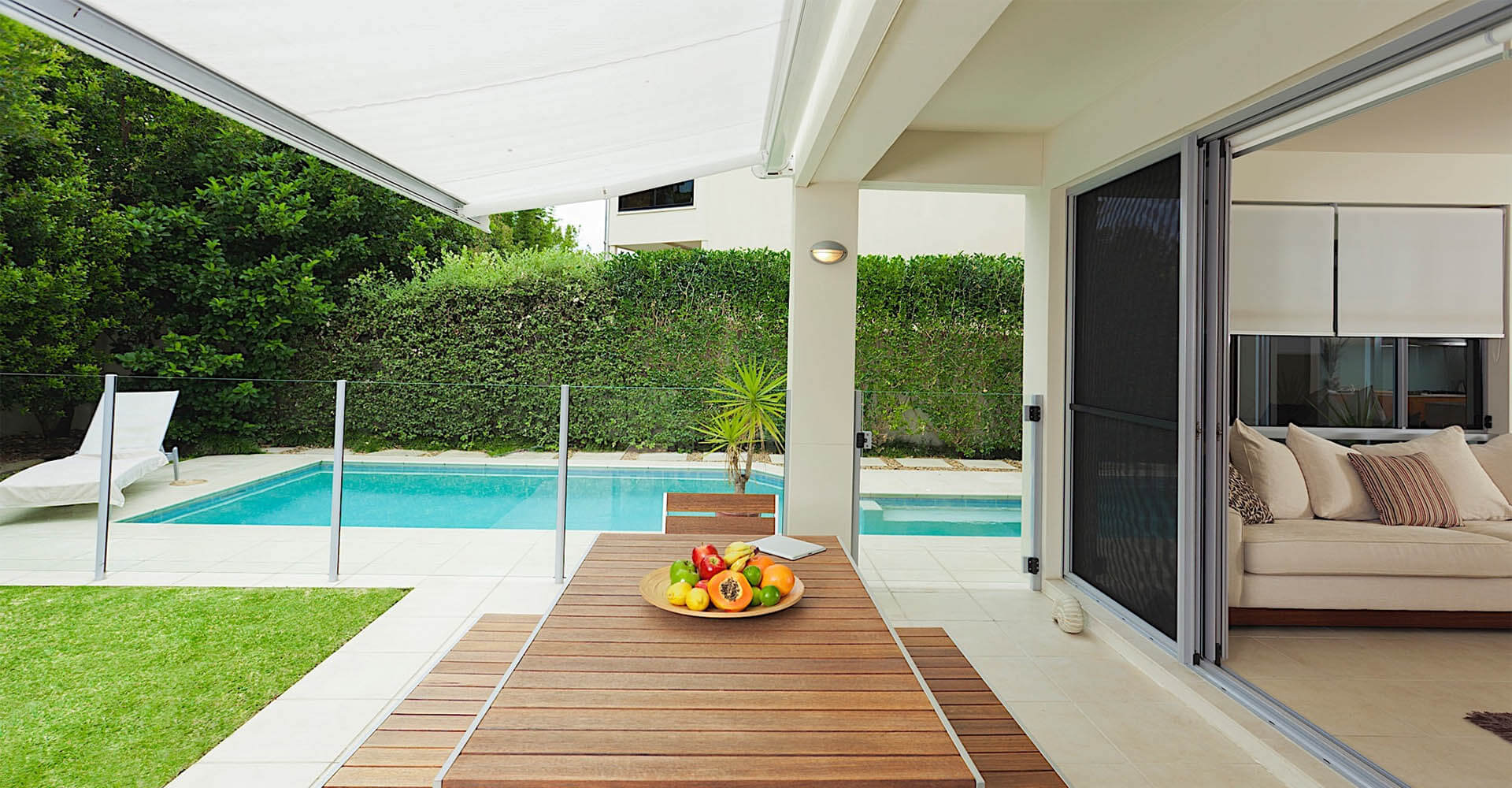 Awning on terrace with open living room and pool in background