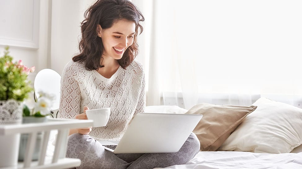 Woman with morning routine on bed with laptop
