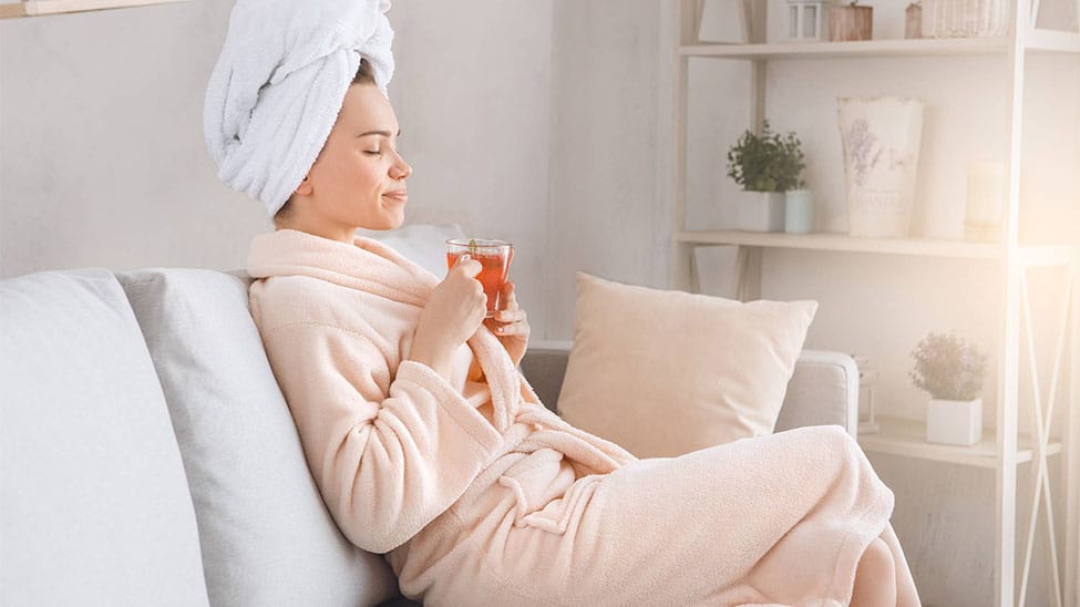 Woman in bathrobe on sofa at home