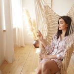 Woman relieves stress in hammock in bedroom