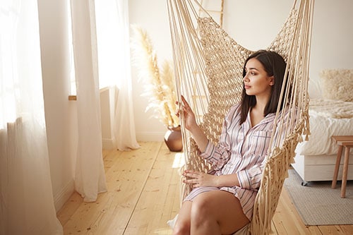 Woman relieves stress in hammock in bedroom