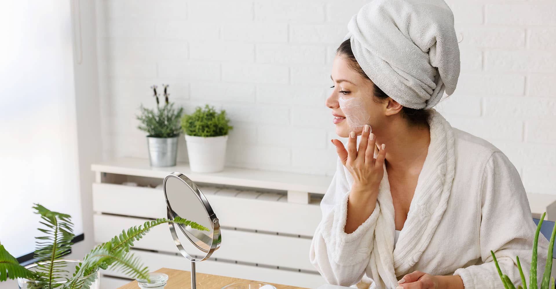 Woman doing facial care at mirror at home