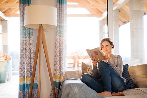Woman enjoying life and relaxing with a book on sofa at home