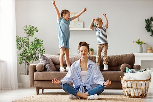 Mother performs relaxation exercise in the form of meditation next to her children