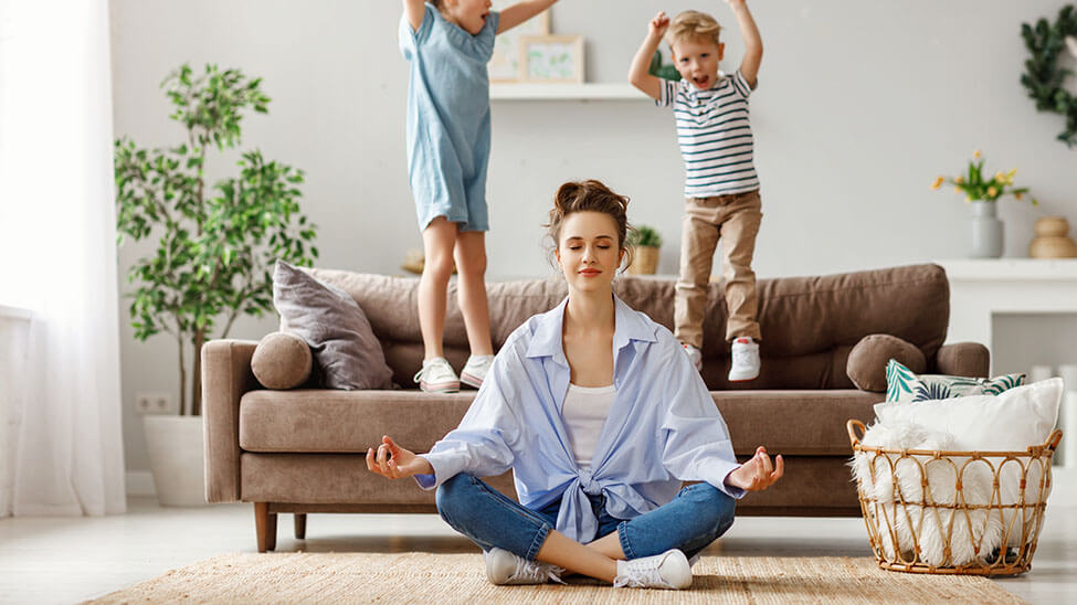 Mother performing relaxation exercise in the form of meditation next to her children