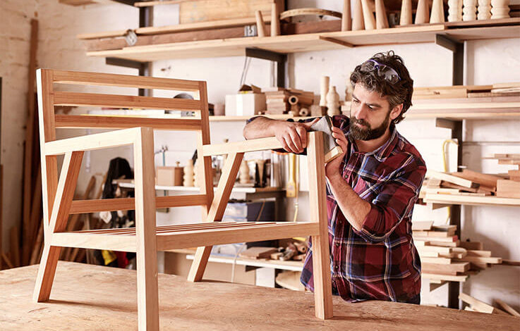 DiY-Heimwerker, der in Garage oder Werkstatt einen Holzstuhl schleift