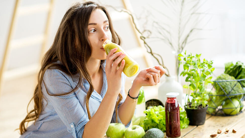 Frau trinkt einen selbstgemachten Saft aus Obst oder Gemüse