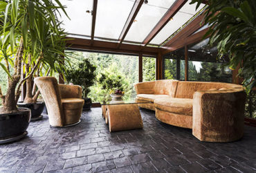 Nobler Kaltwintergarten mit Sofa, Glastisch und großen Pflanzen