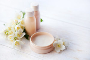 Offenes Wellness-Creme-Produkt & Duft-Gläschen mit Blumen verziert