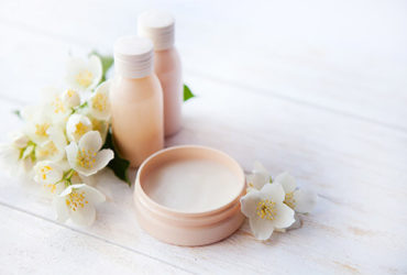 Offenes Wellness-Creme-Produkt & Duft-Gläschen mit Blumen verziert