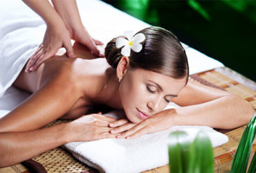 Aromaölmassage für eine schöne Frau, die auf einer Bambusliege und einem weißen Handtuch liegt