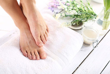 Fußpflege mit Handtuch, Creme, Öl und Blumen