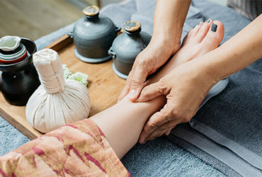 Fußreflexzonenmassage, bei der die Hände des Masseurs und ein Bein der zu massierenden Person sichtbar sind