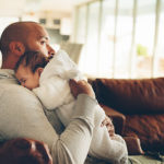 Baby schläft auf Schulter seines Vaters ein