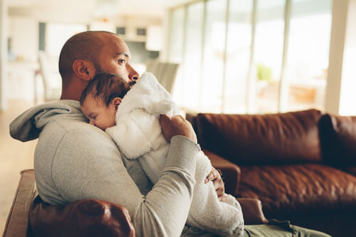 Baby schläft auf Schulter seines Vaters ein